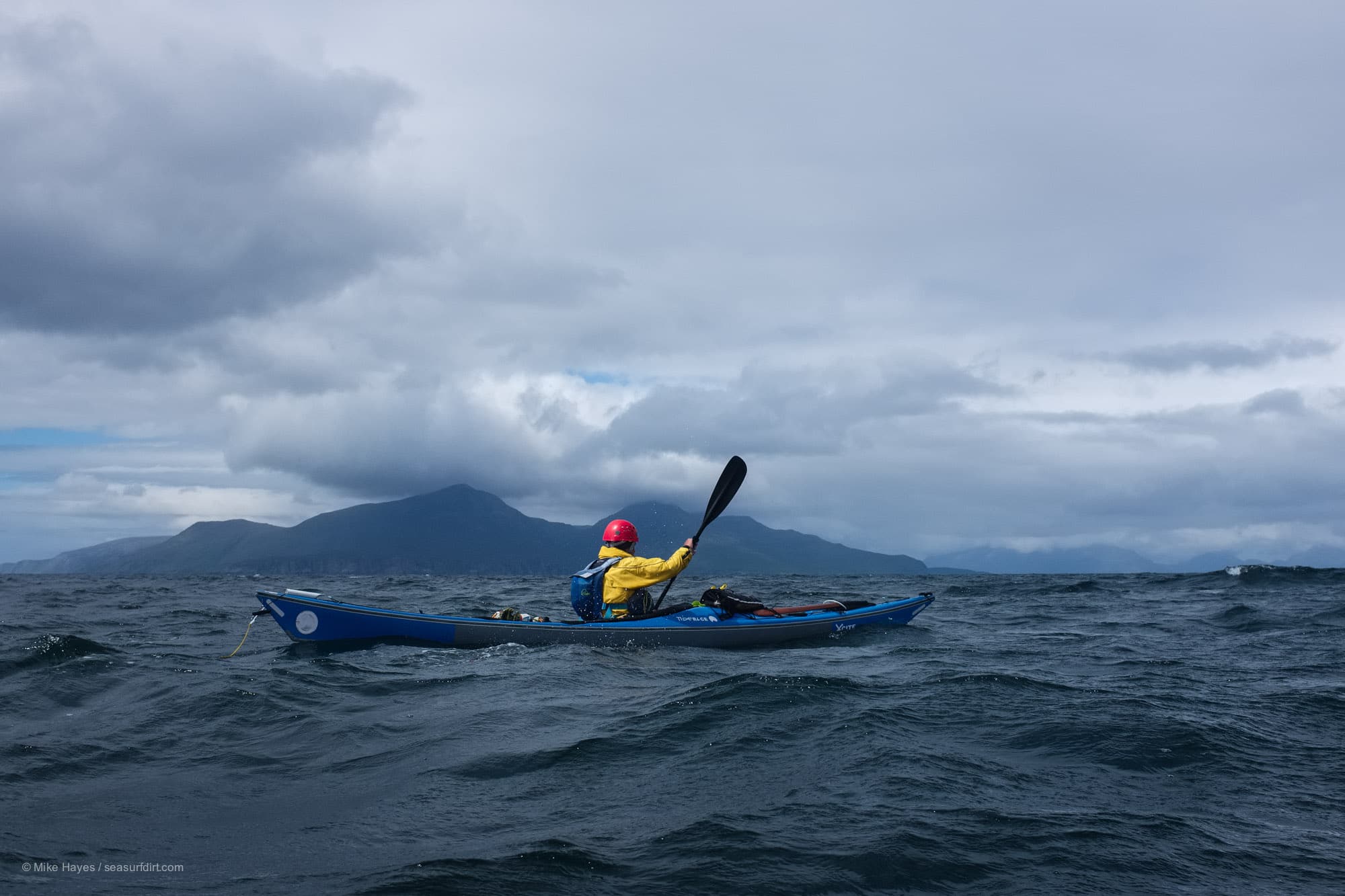 Sea kayaking between the Isle of Muck and the Isle of Eigg with the mountains of Rum in the background